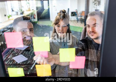 Businessman with colleagues discussing over adhesive notes Stock Photo