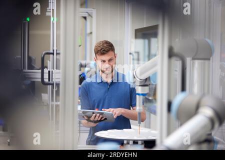 Engineer operating robotic machine in industry Stock Photo