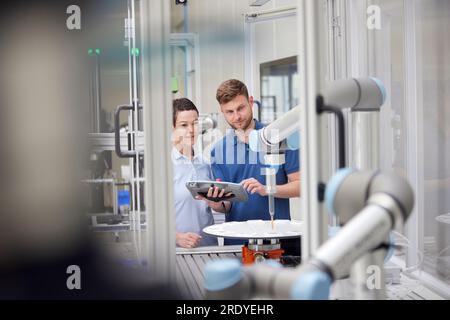Technicians analyzing robotic machine in industry Stock Photo