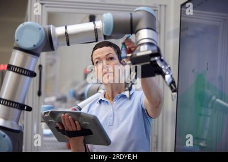 Engineer checking robotic arm holding equipment in industry Stock Photo
