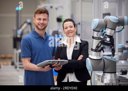 Confident manager and technician standing next to machine in industry Stock Photo