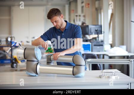 Focused engineer repairing robotic arm in industry Stock Photo