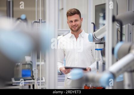 Smiling technician holding tablet PC in industry Stock Photo