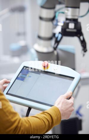 Hands of technician holding modern controller in factory Stock Photo