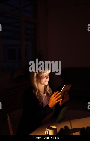 Blond woman using tablet PC at night Stock Photo