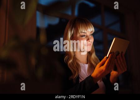 Smiling woman using tablet PC at night Stock Photo