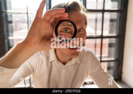 Happy mature businessman looking through magnifying glass Stock Photo