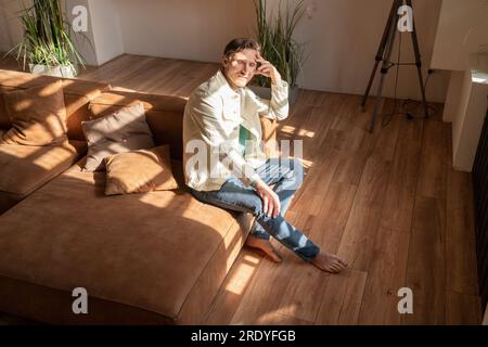Contemplative mature man sitting on sofa at home Stock Photo