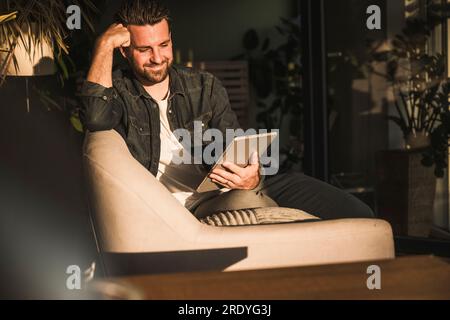 Smiling man using tablet PC at home Stock Photo