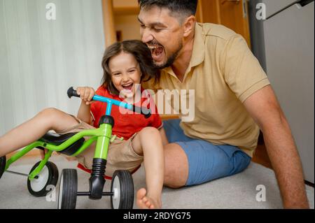 Happy father playing with son sitting on cycle Stock Photo