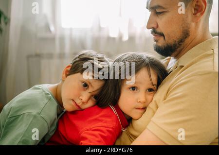 Father embracing children at home Stock Photo