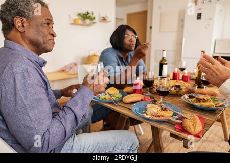 Senior man and woman talking with friends sitting at dining table Stock Photo
