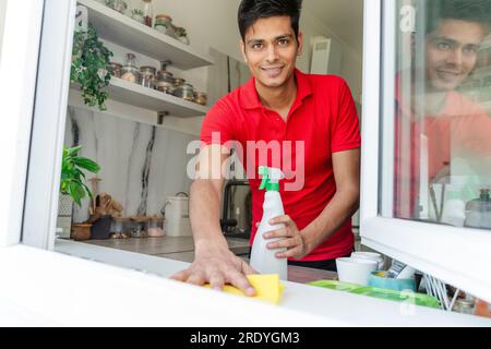 Man cleaning kitchen window sill at home Stock Photo