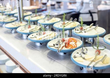 Creatively style the buffet table in the hotel restaurant. Tomatoes with mozzarella and olives on a plate, she led other plates of cheese and herbs. Stock Photo