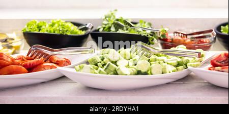 Fresh vegetables, cucumbers, tomatoes and lettuce in bowls on buffet table in hotel restaurant. Stock Photo