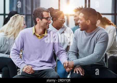 Happy multiethnic employees having fun while discussing project, sharing ideas, informal brainstorming sitting on chairs Stock Photo