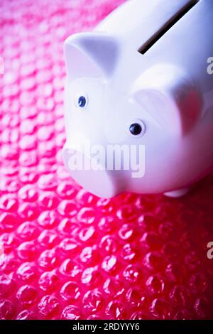 White porcelain piggy bank on red bubble wrap Stock Photo