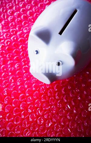 White porcelain piggy bank on red bubble wrap Stock Photo