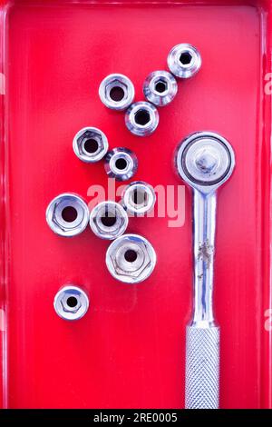Top view on ratchet drill and socket wrenches in red toolbox Stock Photo