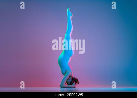 Pregnant woman doing headstand exercise in neon Stock Photo