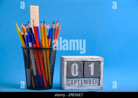 Organizer with pencils and ruler, stationery stand and wooden calendar with date September 01 blue background Stock Photo
