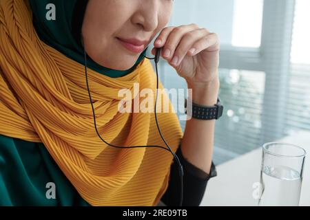 Cropped image of smiling muslim businesswoman answering phone call from business colleague Stock Photo