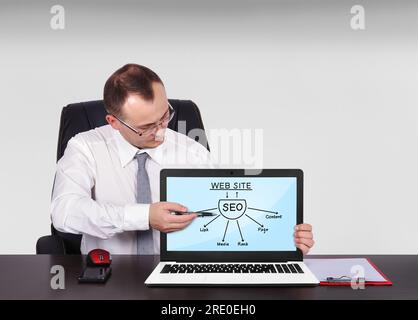 businessman sitting in office and pointing to screen notebook with seo scheme Stock Photo