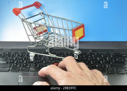 small shopping cart on laptop and computer screen background concepts shop on line Stock Photo