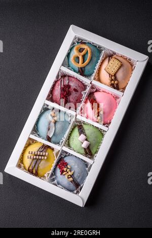 Delicious sweet colorful mochi desserts or ice cream with rice dough and toppings in a cardboard box on a dark concrete background Stock Photo