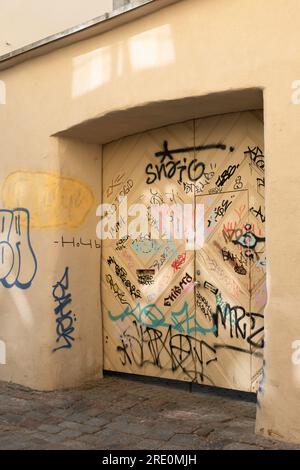 Ocher-colored wall and garage door in a street are sprayed with graffiti Stock Photo