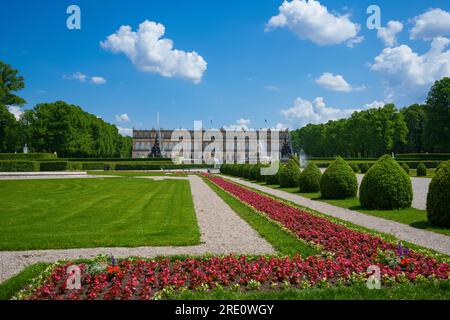 Summer garden landscape. Blue sky and white clouds, trees, grass, red flowers. Schloss Herrenchiemsee is located on the castle island of Chiemsee, Ger Stock Photo