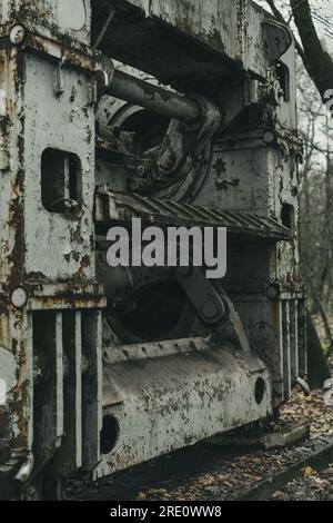 An old defunct big sheet metal working machine in the forest. Iron and steel production. Industrial history machine. Abandoned and rusted machinery. Stock Photo