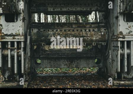 Detail of an old abandoned and rusted sheet metal working machine in the forest. Iron and steel production. Industrial history machine. Stock Photo