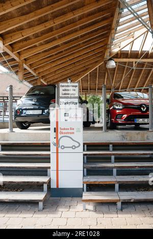 Schiltach, Germany - Jul 14, 2022: German public parking - EV charging point with a wooden terrace in background. Daytime scene with no people. Stock Photo
