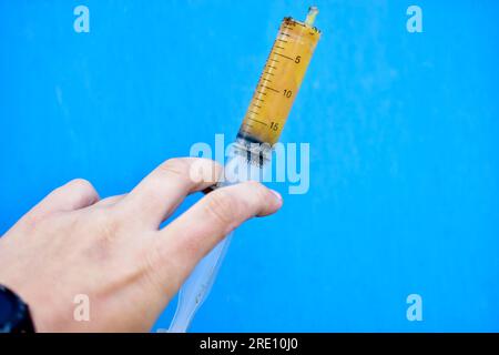 Lubricants in a syringe in your hand on a blue background Stock Photo