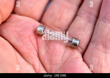 Ordinary wire fuse in a glass shell in the hand Stock Photo