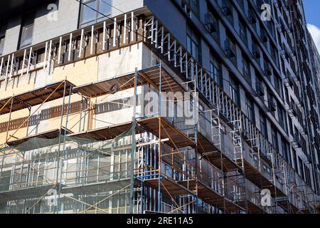 Extensive scaffolding providing platforms for work in progress on a new apartment block. Tall building under construction with scaffolds. Construction Stock Photo