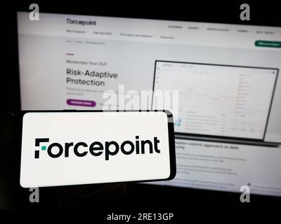 Person holding smartphone with logo of US cybersecurity company Forcepoint LLC on screen in front of website. Focus on phone display. Stock Photo