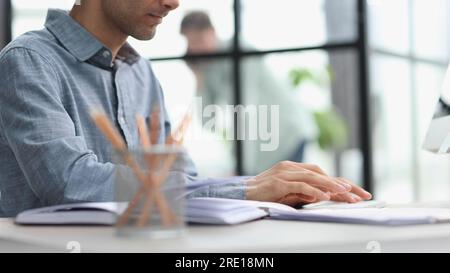 Side view of confident bearded concentrated businessman works on laptop while sitting at the table Stock Photo