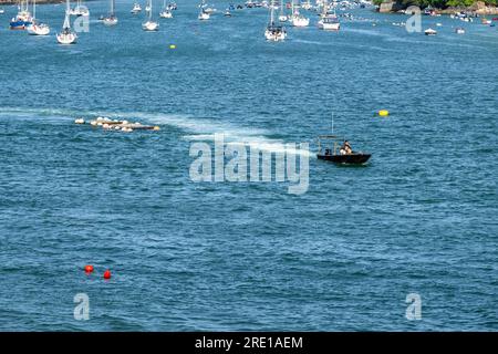 Small inshore boat towing crab nets along the Salcombe estuary in calm water with yachts mored in the background on a summers day. Stock Photo