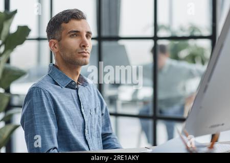 A young pensive man works in the office and thinks about something. Stock Photo