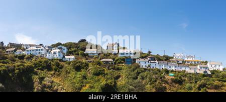 Landscape panorama of holiday cottages and houses perched on a cliff top in Sunny Cornwall with a sea view and copy space Stock Photo