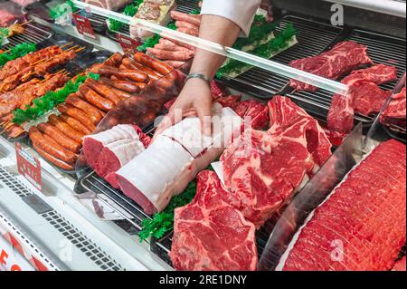Butcher's in a supermarket. Butcher's taking a roast beef, meat for sale in a butcher's shop window Stock Photo