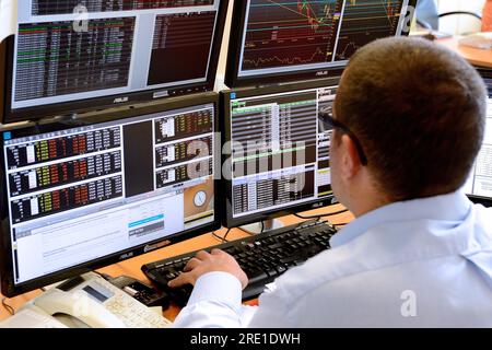 Private brokerage: trader in front of computer screens trading on futures markets. Trading room. Consultation of the stock exchanges prices and the fl Stock Photo