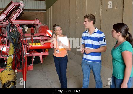 Visit from a chartered accountant to a young couple’s farm. Chartered accountant and couple of young farmers visiting the farm, looking at the equipme Stock Photo