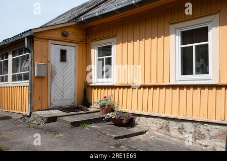 Simple yellow painted wooden house with white door and window frames in Trakai, Lithuania Stock Photo