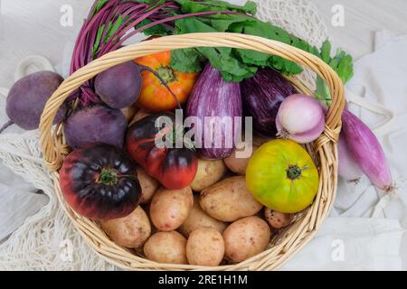 Basket with various vegetables. Potatoes, beets, tomatoes, shallots, eggplants. Country style. Top view. Stock Photo