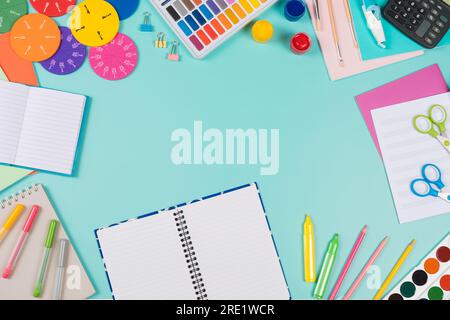 Back to school background. Colored pencils, books, notebooks, pens, watercolor paint, scissors, math fractions, calculator on pastel green background Stock Photo