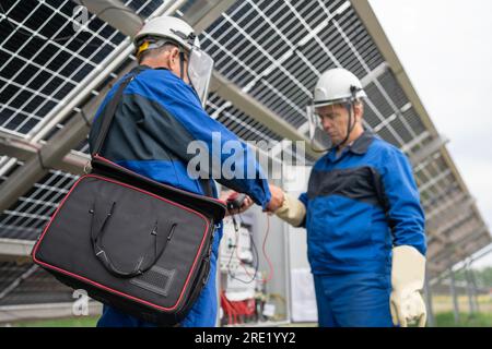 Two Service Engineers or electrician working on checking transformer site and solving problem for green energy solar power plant operation. Technician Stock Photo