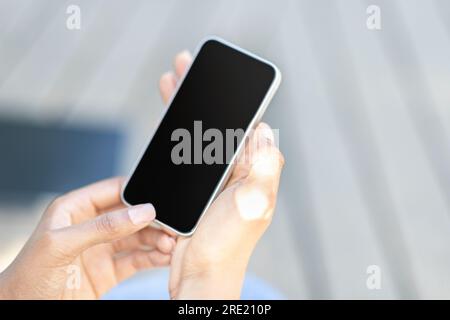 Cropped of black woman hands using smartphone, blurred outdoor background Stock Photo